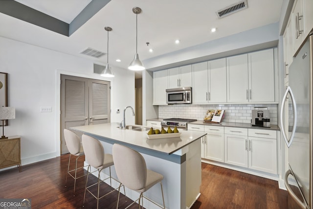 kitchen featuring a center island with sink, sink, appliances with stainless steel finishes, white cabinets, and pendant lighting