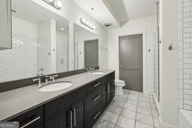 bathroom with vanity, tile patterned floors, toilet, and tiled shower