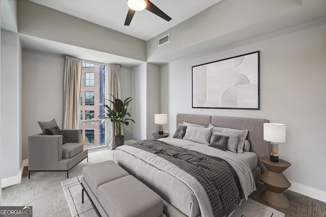 bedroom featuring ceiling fan, multiple windows, and light colored carpet