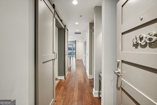 hall with dark wood-type flooring and a barn door