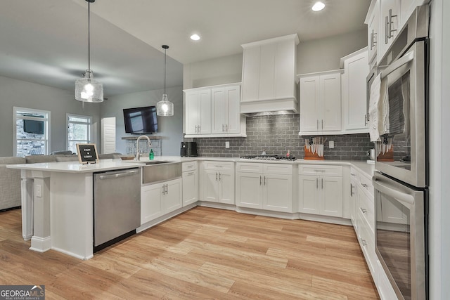 kitchen featuring white cabinets, stainless steel appliances, kitchen peninsula, and hanging light fixtures