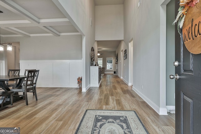 foyer entrance with light hardwood / wood-style flooring, beamed ceiling, and coffered ceiling