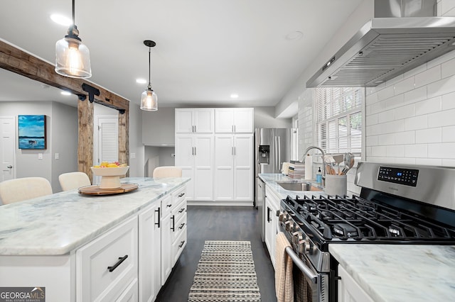 kitchen featuring wall chimney range hood, a barn door, decorative backsplash, sink, and gas range