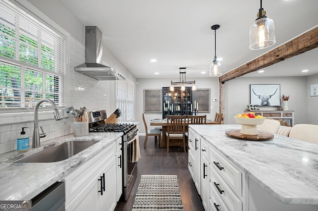 kitchen featuring dark hardwood / wood-style flooring, wall chimney exhaust hood, pendant lighting, and appliances with stainless steel finishes