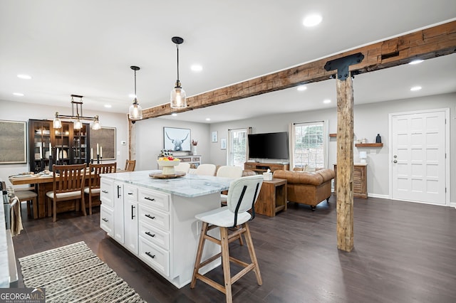 kitchen featuring light stone countertops, decorative light fixtures, a center island, white cabinets, and dark hardwood / wood-style flooring