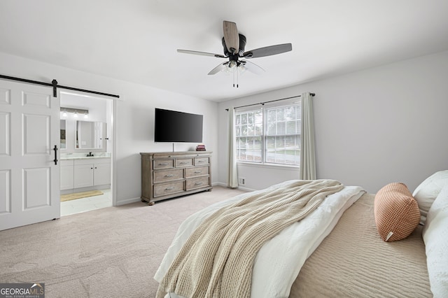 carpeted bedroom featuring sink, a barn door, ceiling fan, and ensuite bath