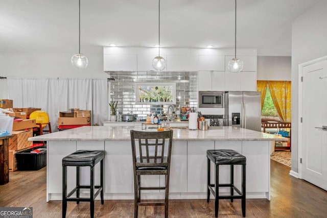 kitchen with white cabinetry, stainless steel appliances, dark wood-type flooring, and an island with sink