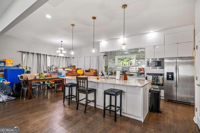 kitchen with stainless steel appliances, an island with sink, and dark hardwood / wood-style flooring