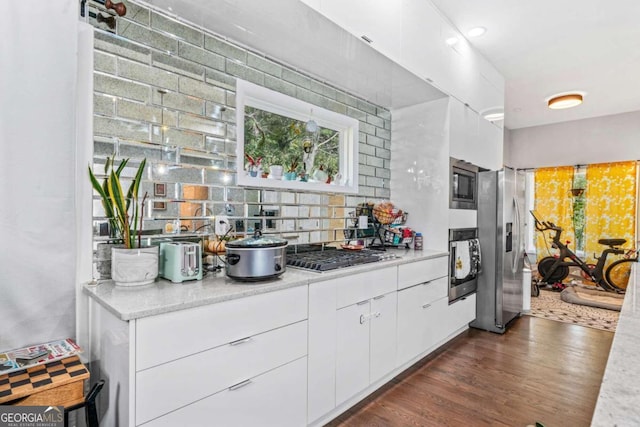 bar with dark wood-type flooring, backsplash, stainless steel appliances, and white cabinets