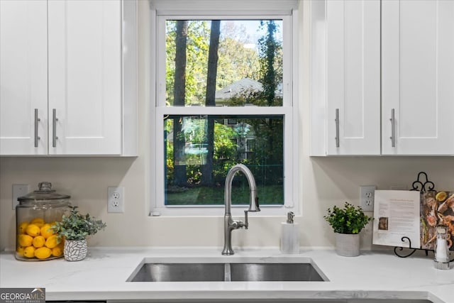 kitchen with white cabinets, light stone countertops, and sink