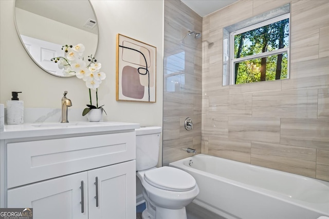 full bathroom featuring vanity, tiled shower / bath combo, and toilet