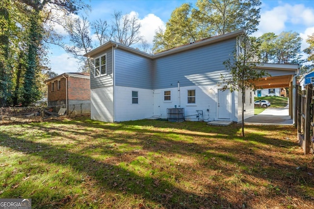 back of house with central AC unit and a yard