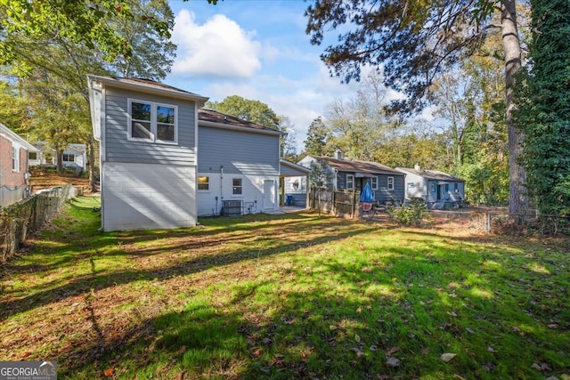 rear view of property with a lawn and central air condition unit