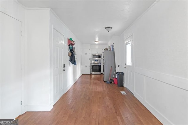 hall featuring ornamental molding and light hardwood / wood-style flooring