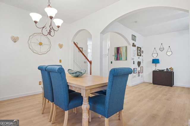 dining room with light wood-type flooring and an inviting chandelier