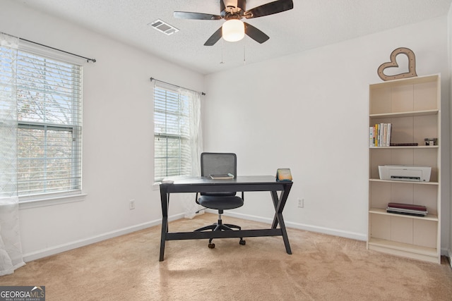 office featuring a textured ceiling, light carpet, and ceiling fan