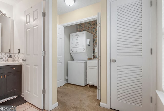 clothes washing area featuring stacked washing maching and dryer, a textured ceiling, and light carpet