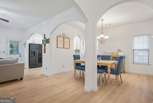 dining area featuring ceiling fan with notable chandelier, a textured ceiling, and light hardwood / wood-style flooring