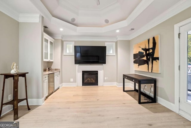 living room with sink, a raised ceiling, light hardwood / wood-style floors, and crown molding