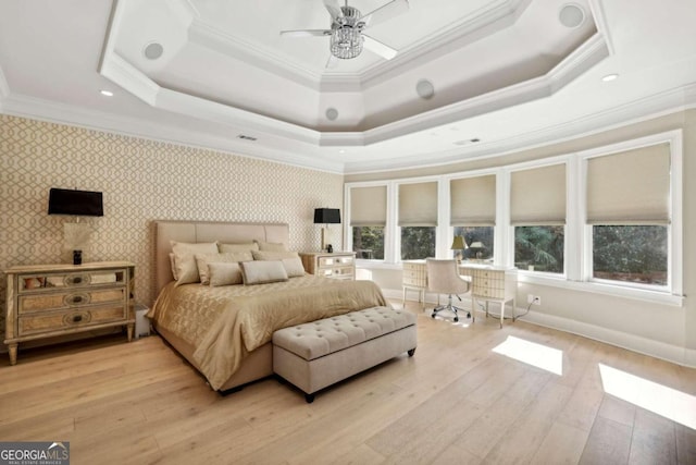 bedroom with ceiling fan, light hardwood / wood-style flooring, and a tray ceiling