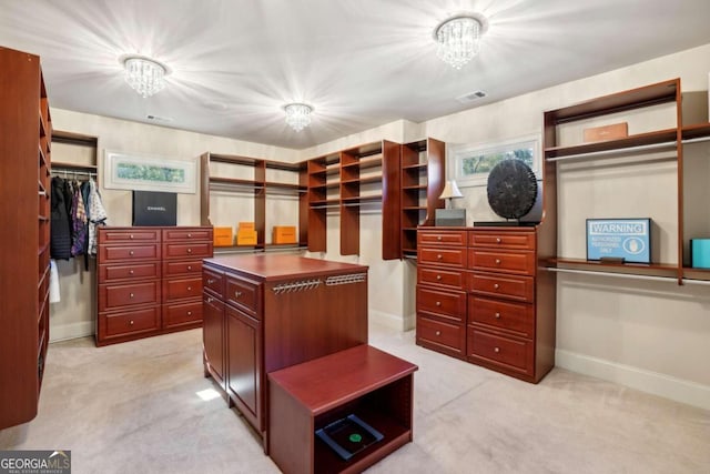 spacious closet with light colored carpet and an inviting chandelier