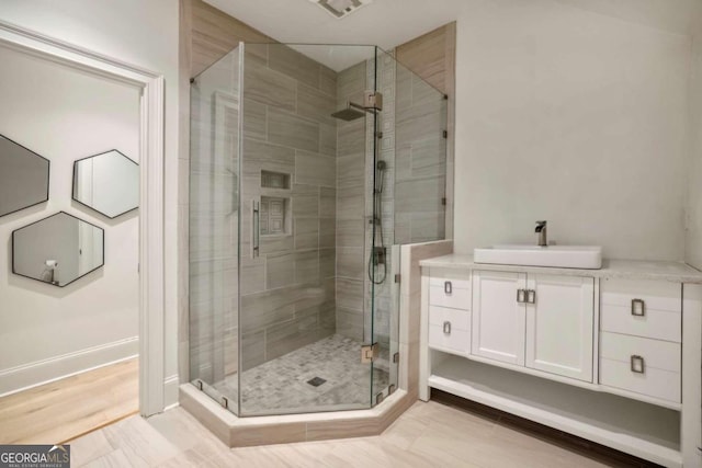 bathroom featuring walk in shower, hardwood / wood-style floors, and vanity