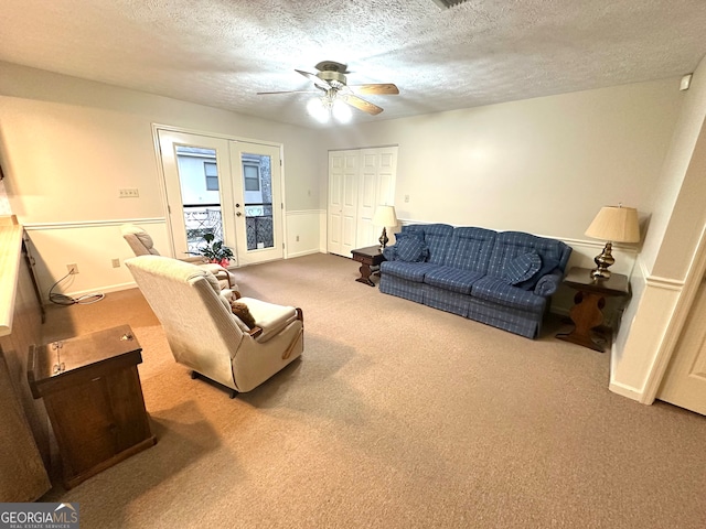 living room with a textured ceiling, carpet flooring, and ceiling fan