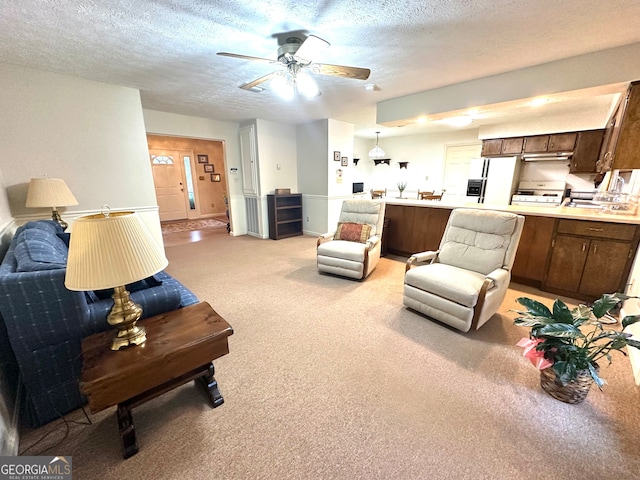 living room featuring ceiling fan, a textured ceiling, and light carpet