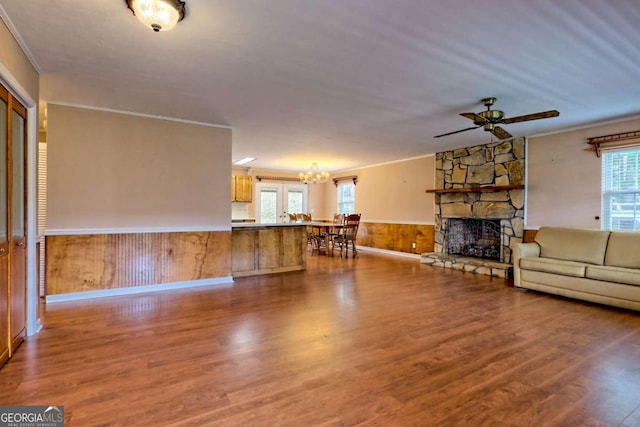 unfurnished living room featuring wood walls, wood-type flooring, a healthy amount of sunlight, and crown molding