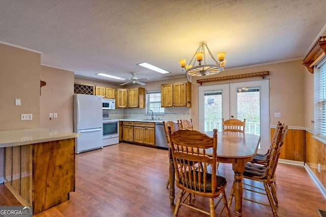 dining space featuring a textured ceiling, sink, wood-type flooring, and ceiling fan with notable chandelier