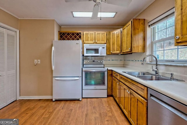 kitchen with decorative backsplash, sink, crown molding, light wood-type flooring, and white appliances