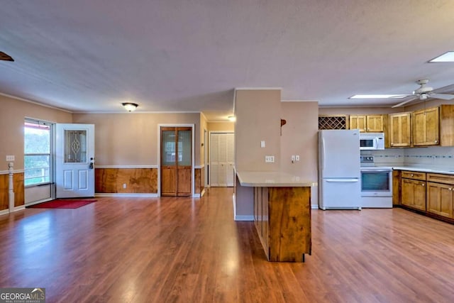 kitchen featuring backsplash, wooden walls, hardwood / wood-style flooring, white appliances, and ceiling fan