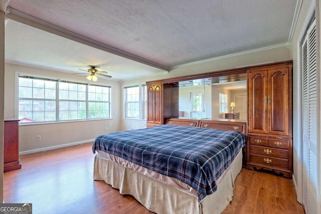 bedroom featuring crown molding, a textured ceiling, ceiling fan, and light hardwood / wood-style flooring