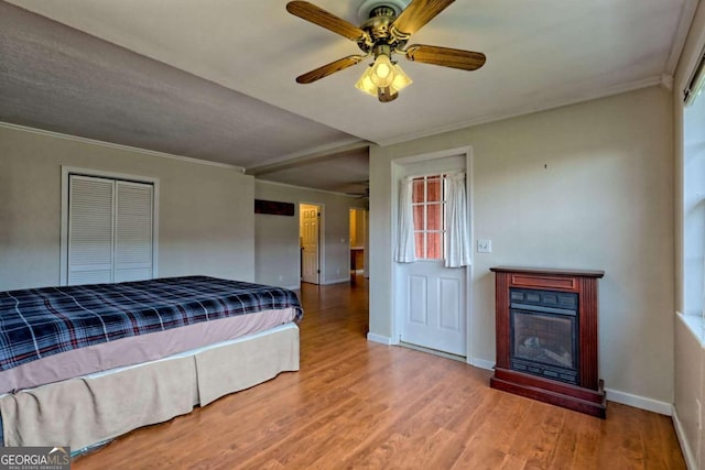 unfurnished bedroom with hardwood / wood-style floors, ceiling fan, a closet, and crown molding