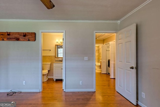 bedroom featuring ornamental molding, hardwood / wood-style floors, ensuite bath, and ceiling fan