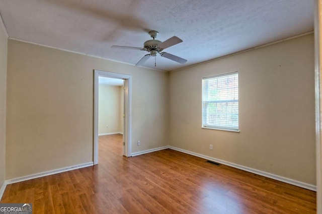 empty room with hardwood / wood-style flooring, ceiling fan, a textured ceiling, and crown molding