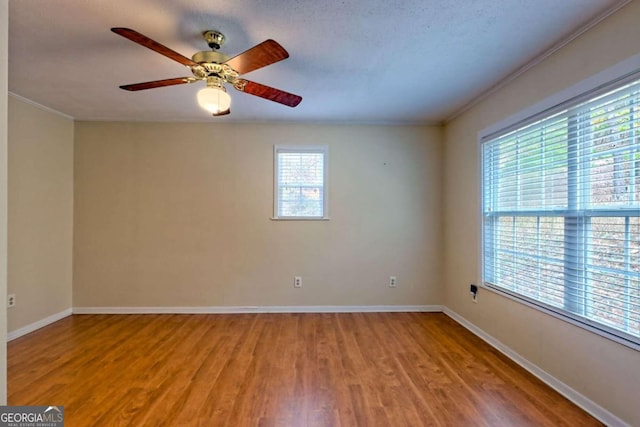 empty room featuring hardwood / wood-style floors, a wealth of natural light, and ornamental molding