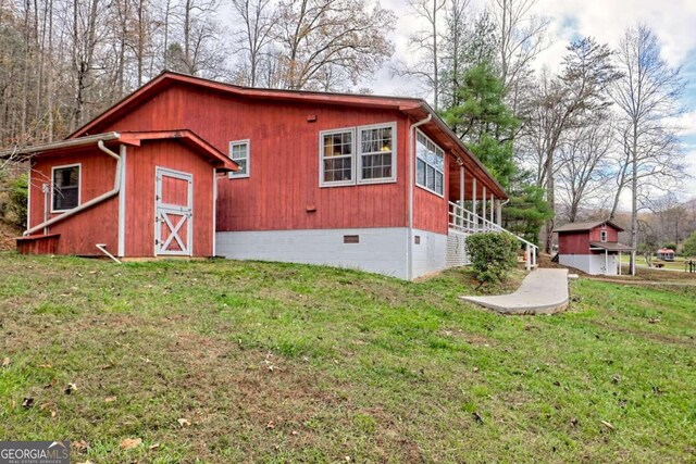 view of side of home with a yard and an outdoor structure