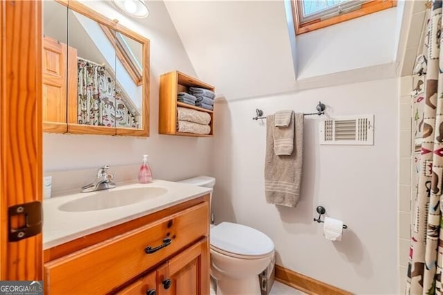 bathroom with vanity, toilet, and vaulted ceiling with skylight