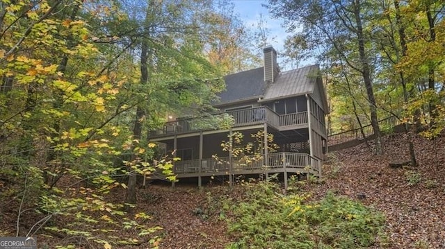 rear view of property featuring a sunroom and a wooden deck