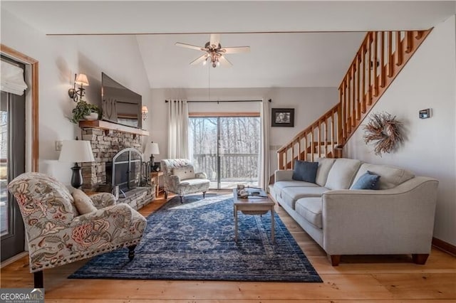 living room with a fireplace, vaulted ceiling, ceiling fan, and light hardwood / wood-style flooring