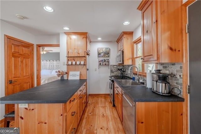 kitchen with a kitchen bar, stainless steel appliances, sink, tasteful backsplash, and light hardwood / wood-style flooring