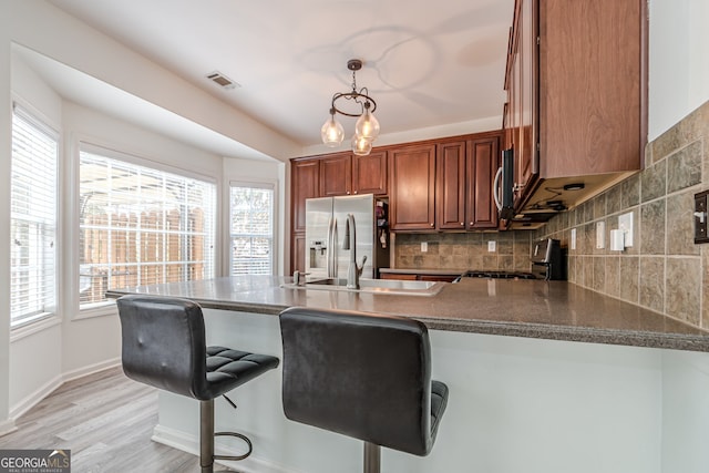 kitchen with kitchen peninsula, stainless steel fridge with ice dispenser, a breakfast bar, and black range oven