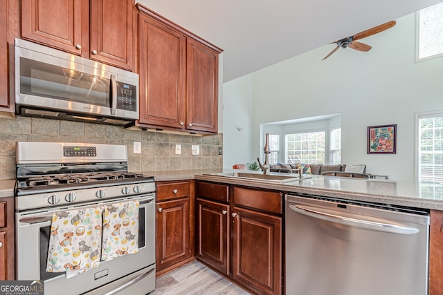 kitchen featuring stainless steel appliances, light hardwood / wood-style floors, sink, ceiling fan, and backsplash