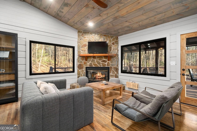 sitting room with vaulted ceiling, wood ceiling, a fireplace, and wood finished floors