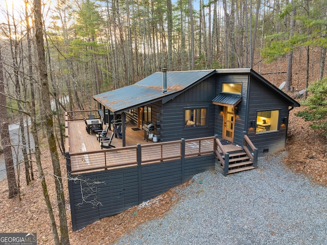 rustic home featuring crawl space, metal roof, a deck, and a view of trees