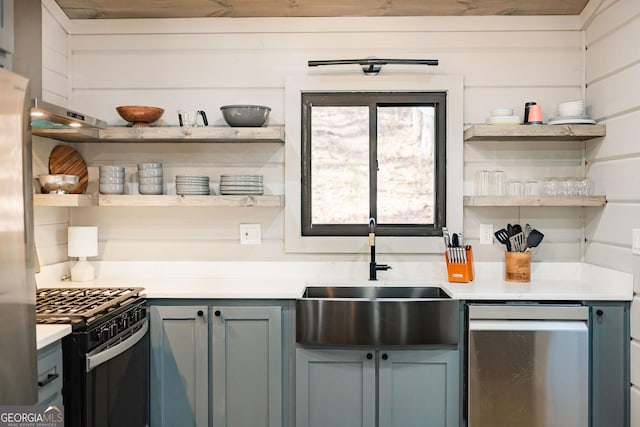 kitchen featuring open shelves, light countertops, black gas range, gray cabinetry, and a sink