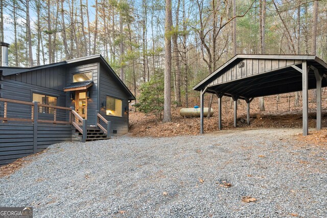 view of side of home with board and batten siding, a detached carport, and driveway