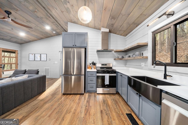 kitchen with wooden ceiling, a sink, light countertops, appliances with stainless steel finishes, and wall chimney range hood