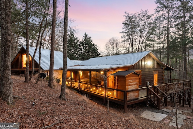 rear view of property with a deck, stairs, and metal roof